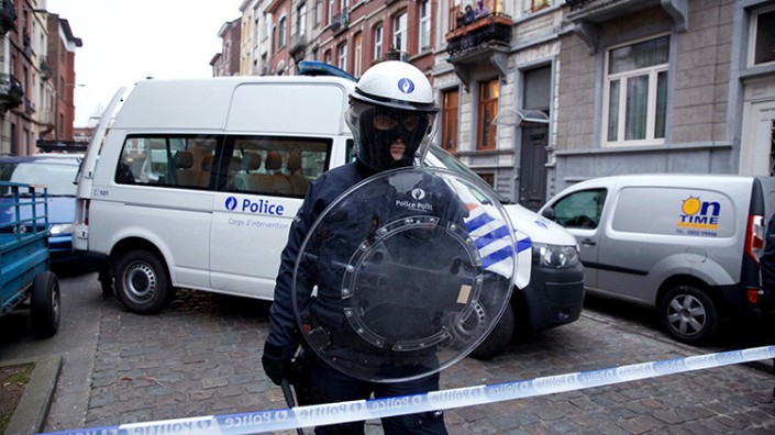 Un policía monta guardia tras fijar un perímetro de seguridad en el barrio de Molenbeek (Bruselas)